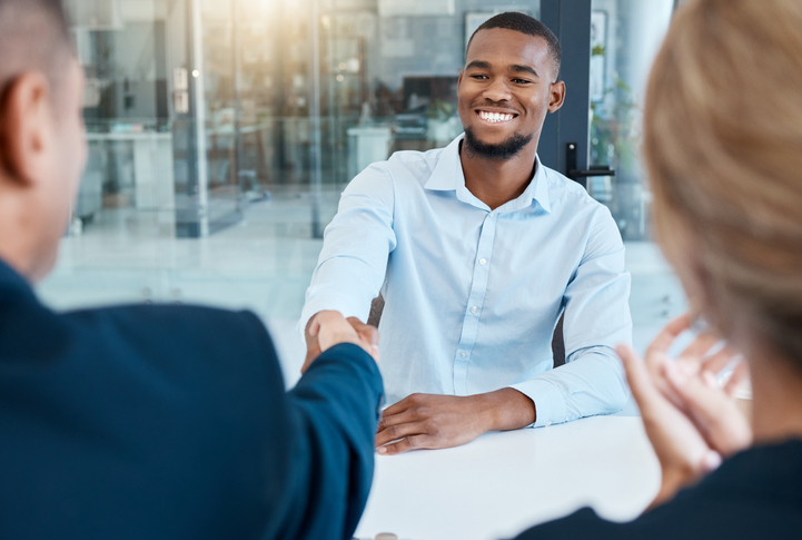 Shaking hands, interview and business people give a handshake after hiring a new company employee. Onboarding, thank you and management welcome young African worker a job promotion in office meeting